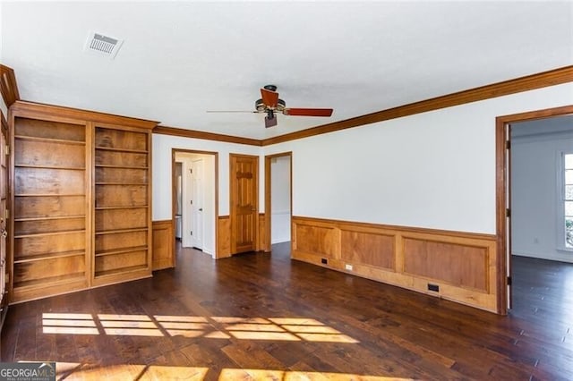 unfurnished room featuring a wainscoted wall, visible vents, a ceiling fan, ornamental molding, and wood finished floors