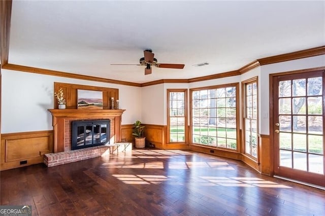 living area featuring plenty of natural light, wainscoting, visible vents, and a brick fireplace