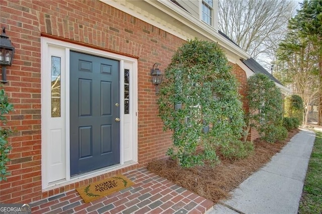 view of exterior entry featuring brick siding