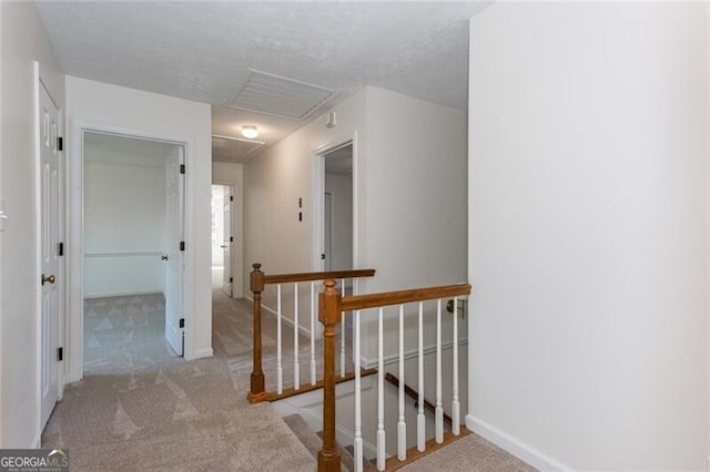 hall with a textured ceiling, carpet, an upstairs landing, and baseboards