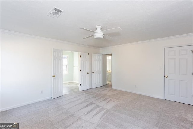 unfurnished bedroom with carpet floors, visible vents, crown molding, and baseboards