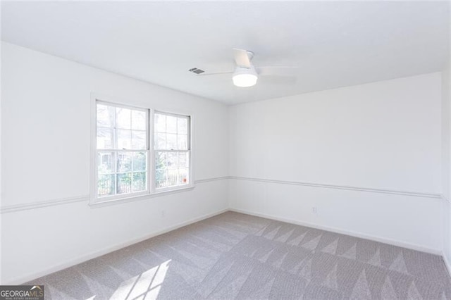 spare room featuring baseboards, ceiling fan, visible vents, and light colored carpet