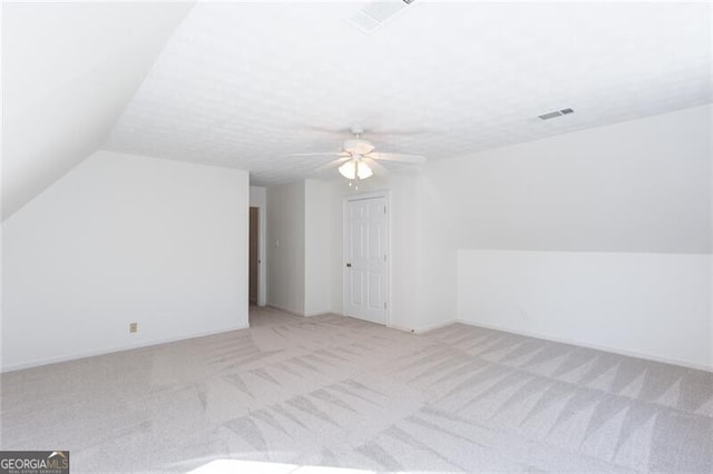 bonus room featuring ceiling fan, visible vents, vaulted ceiling, and light colored carpet