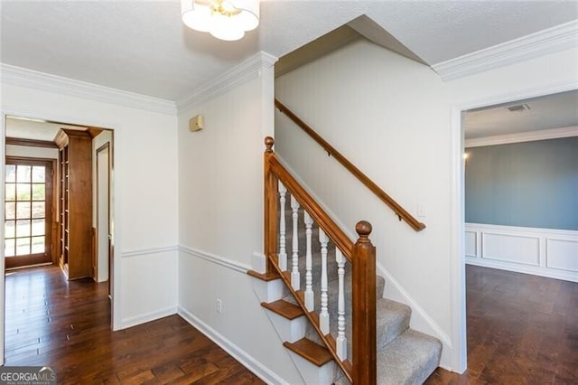 staircase with a wainscoted wall, crown molding, a decorative wall, and wood finished floors