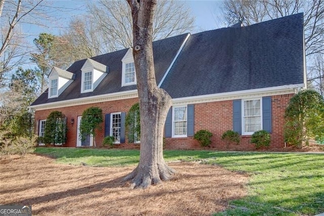 cape cod home with brick siding, a front lawn, and a shingled roof