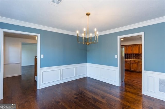 spare room with visible vents, a chandelier, wood finished floors, and ornamental molding