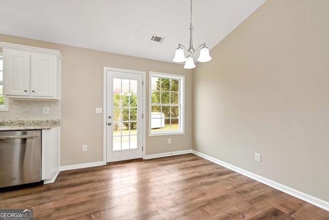 interior space featuring lofted ceiling, visible vents, wood finished floors, a chandelier, and baseboards