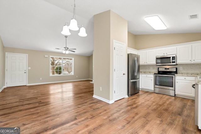 kitchen featuring ceiling fan with notable chandelier, visible vents, white cabinets, appliances with stainless steel finishes, and backsplash