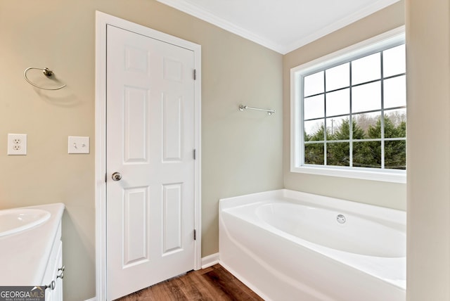 full bathroom featuring wood finished floors, vanity, baseboards, ornamental molding, and a bath