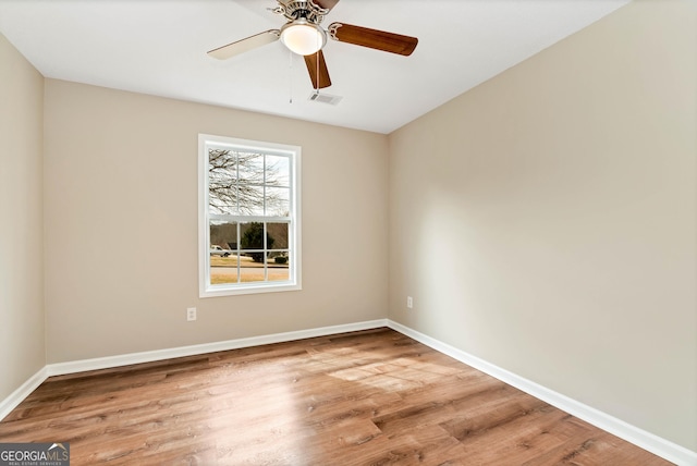 unfurnished room featuring visible vents, baseboards, and wood finished floors