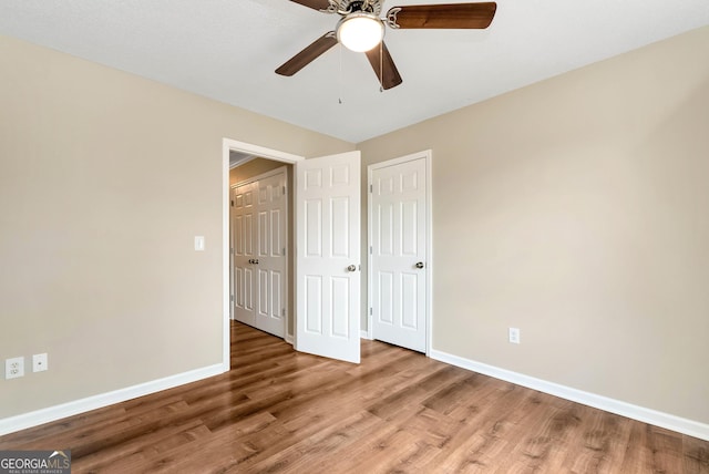 unfurnished bedroom with ceiling fan, baseboards, and wood finished floors