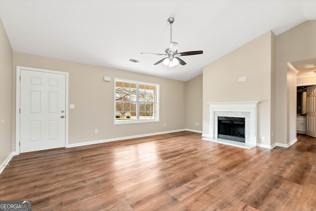 unfurnished living room featuring visible vents, ceiling fan, wood finished floors, vaulted ceiling, and a high end fireplace