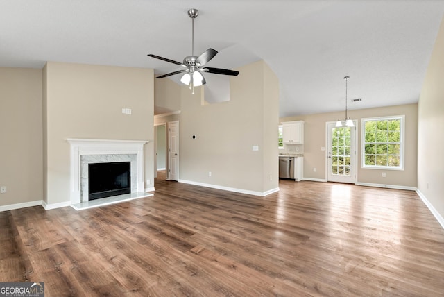 unfurnished living room featuring a fireplace, wood finished floors, a ceiling fan, and baseboards