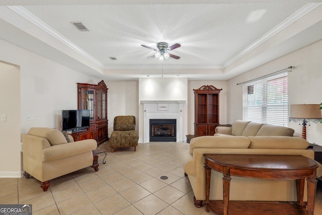 living area featuring a fireplace, light tile patterned floors, a tray ceiling, a ceiling fan, and visible vents