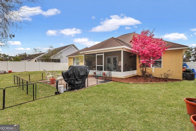 rear view of house with a sunroom, a shingled roof, a yard, a fenced backyard, and stucco siding