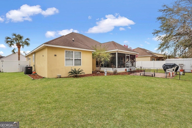 back of house featuring stucco siding, central AC unit, a sunroom, and a lawn