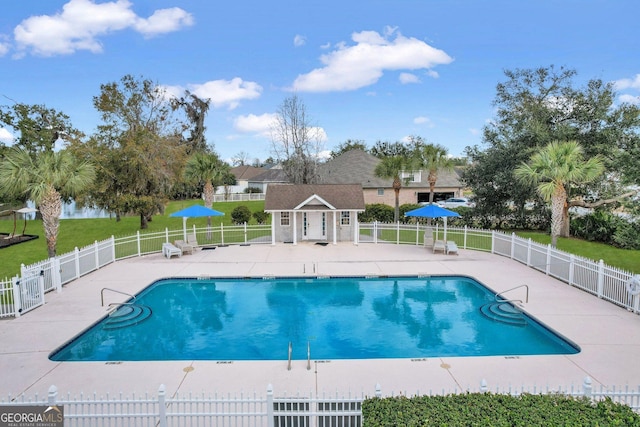 pool featuring a patio area, fence, an outdoor structure, and a lawn