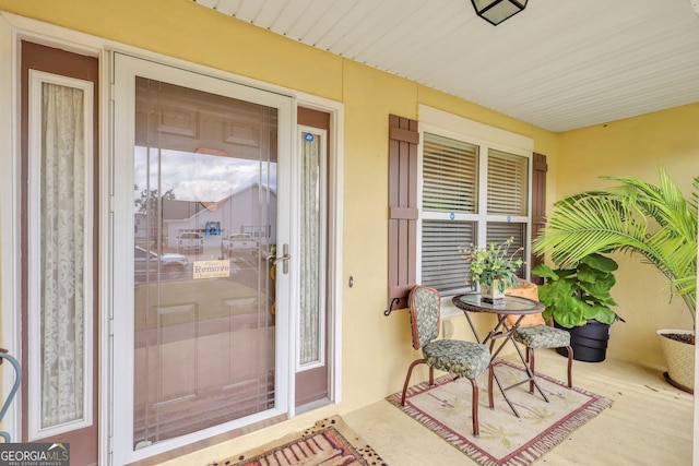 property entrance with a porch and stucco siding