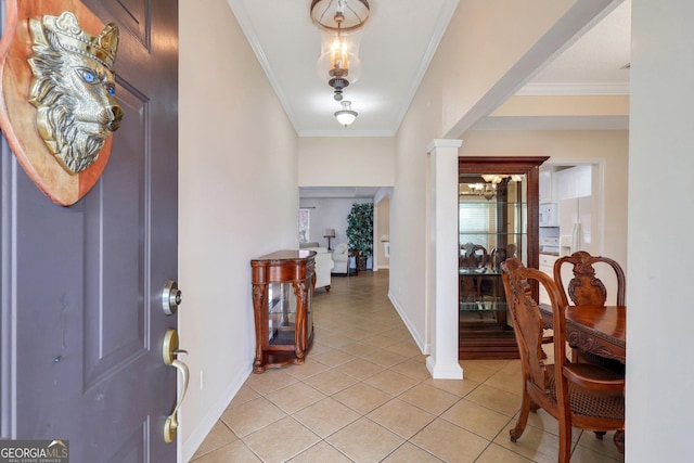 entryway featuring light tile patterned floors, crown molding, ornate columns, and baseboards
