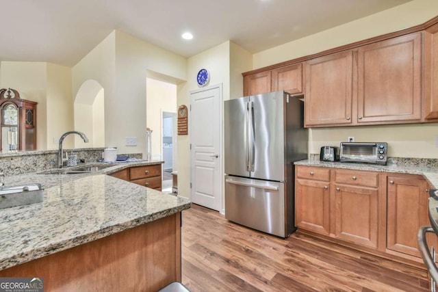 kitchen featuring a sink, freestanding refrigerator, and brown cabinets