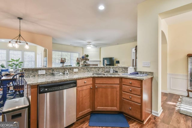 kitchen featuring light stone counters, wood finished floors, a sink, brown cabinets, and dishwasher