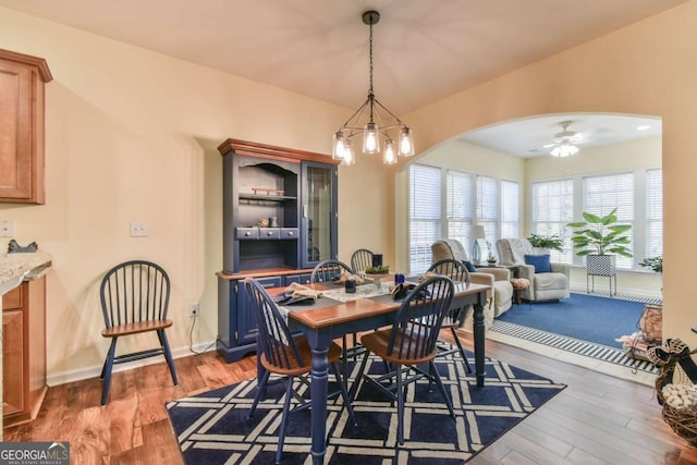 dining room with baseboards, ceiling fan, arched walkways, and wood finished floors