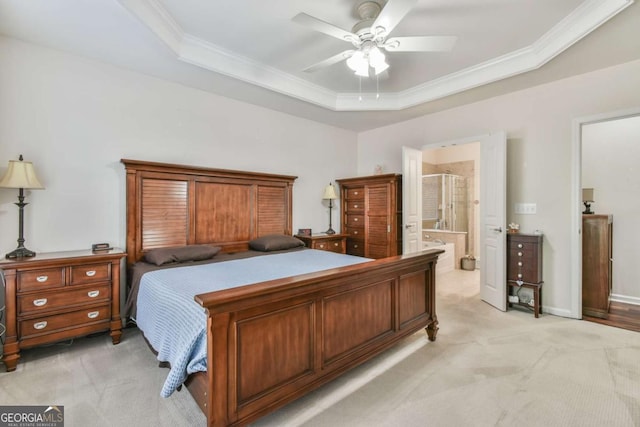 bedroom with light carpet, connected bathroom, a tray ceiling, and crown molding