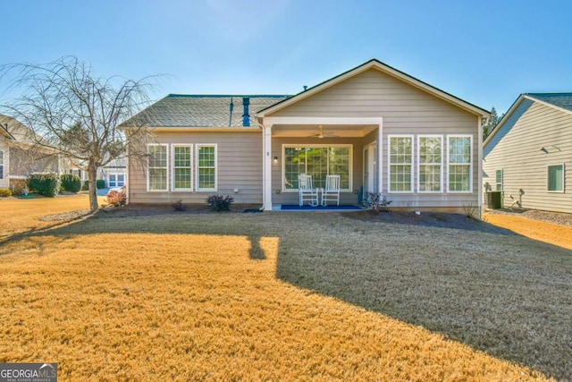 rear view of house featuring roof with shingles, ceiling fan, and a lawn