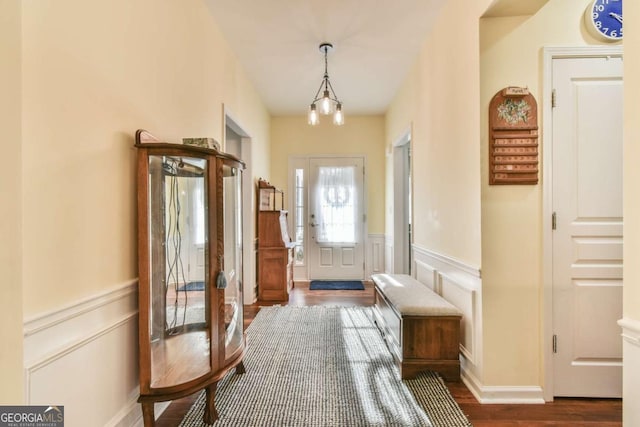 interior space with dark wood-style flooring, wainscoting, and a decorative wall