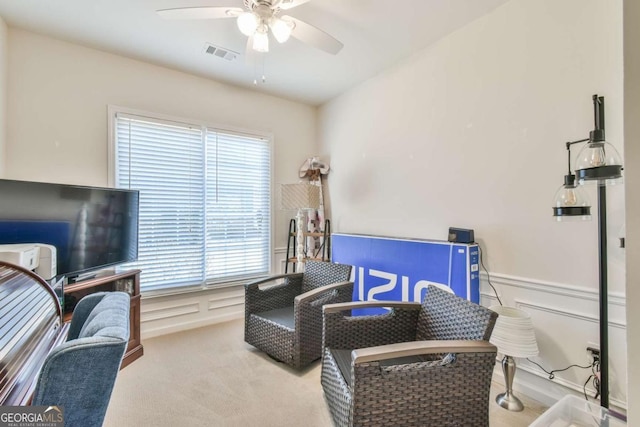 interior space featuring visible vents, a decorative wall, a ceiling fan, and wainscoting