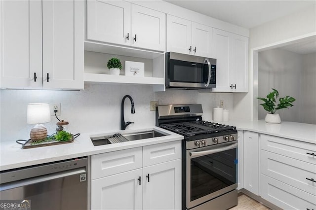 kitchen featuring a sink, white cabinetry, light countertops, appliances with stainless steel finishes, and open shelves