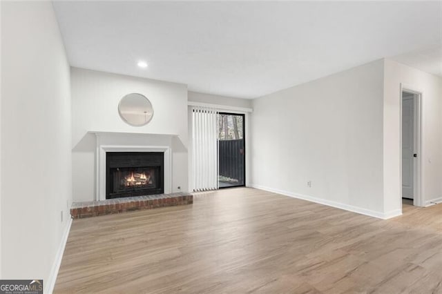 unfurnished living room featuring a fireplace, baseboards, and wood finished floors