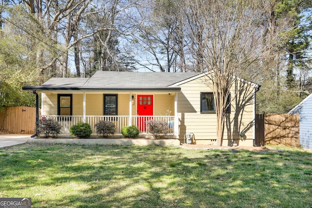 single story home with covered porch, a front yard, and fence