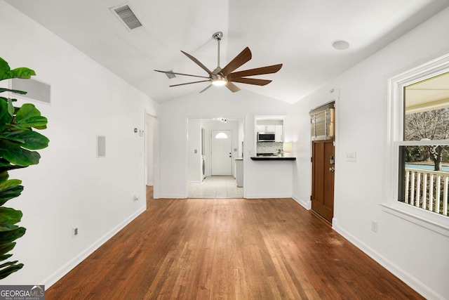 unfurnished living room featuring baseboards, visible vents, ceiling fan, wood finished floors, and vaulted ceiling