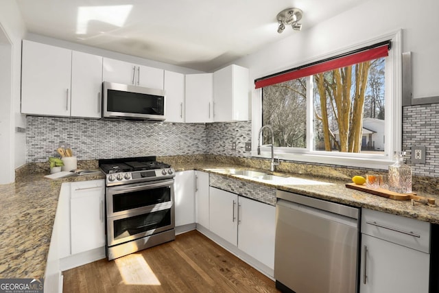 kitchen with white cabinets, dark wood-style floors, appliances with stainless steel finishes, and decorative backsplash