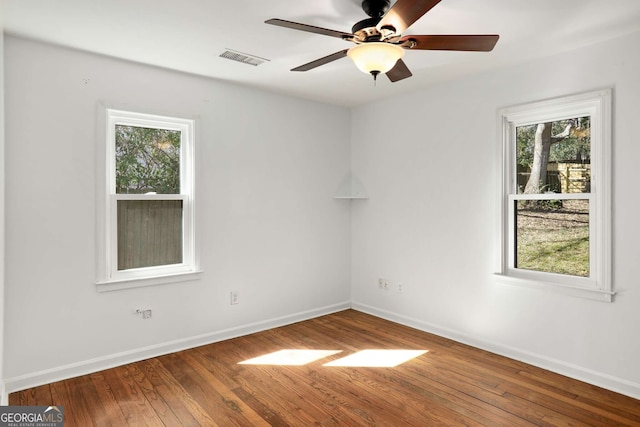 spare room featuring a ceiling fan, hardwood / wood-style flooring, visible vents, and baseboards