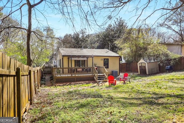 rear view of property with a fenced backyard, central AC unit, a deck, and an outdoor structure