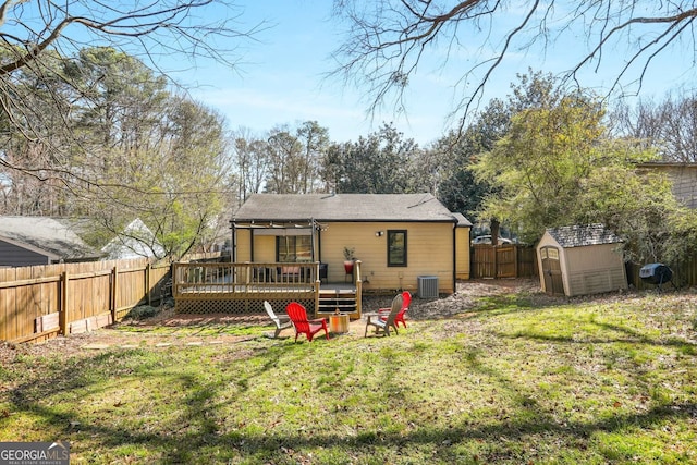 rear view of house with a storage unit, central AC unit, a fenced backyard, an outdoor structure, and a wooden deck