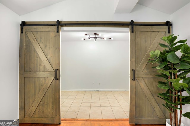 interior space with a barn door, vaulted ceiling, and tile patterned flooring