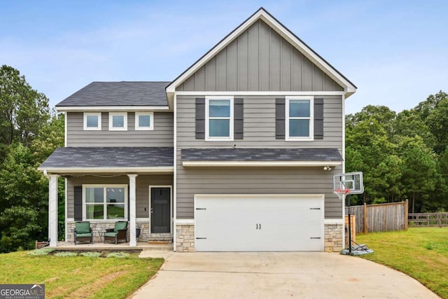 craftsman-style home with covered porch, fence, driveway, a front lawn, and board and batten siding