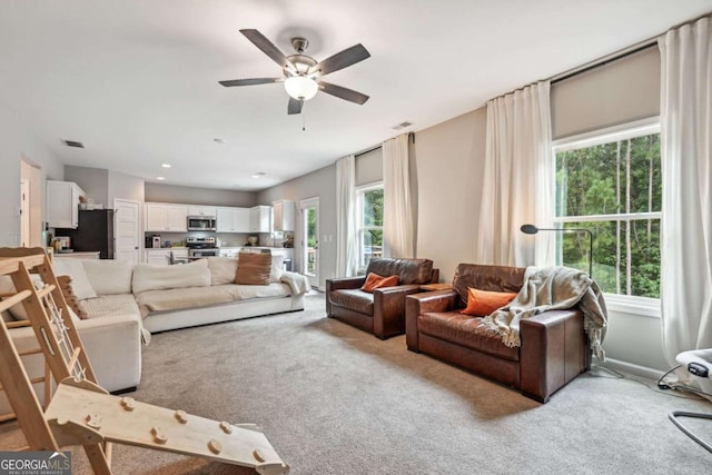 living area with carpet floors, visible vents, plenty of natural light, and a ceiling fan