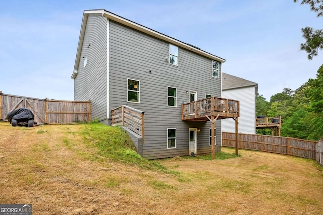 rear view of house with fence, a lawn, and a wooden deck