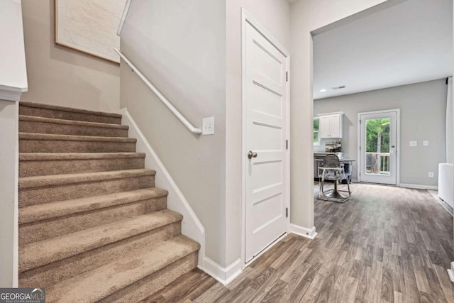 staircase featuring baseboards and wood finished floors