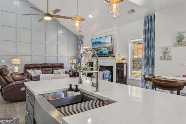 kitchen featuring lofted ceiling, visible vents, a decorative wall, and open floor plan