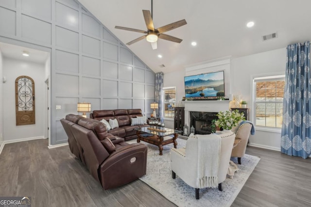 living room featuring high vaulted ceiling, a decorative wall, a premium fireplace, wood finished floors, and visible vents