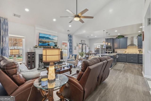 living area featuring wine cooler, recessed lighting, visible vents, wood finished floors, and high vaulted ceiling