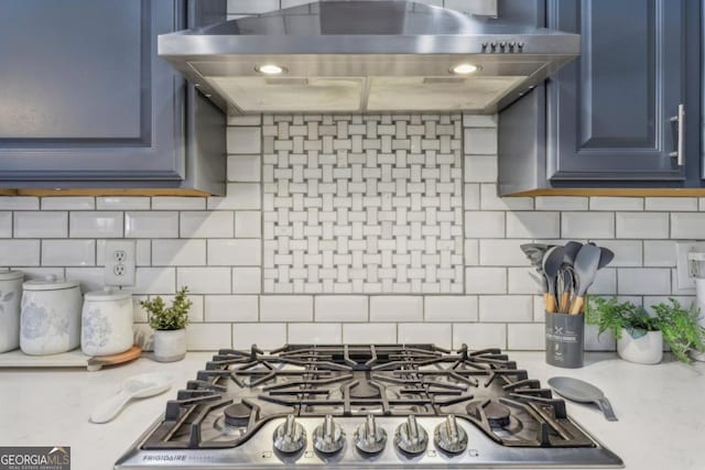 kitchen with blue cabinetry, light countertops, backsplash, ventilation hood, and range