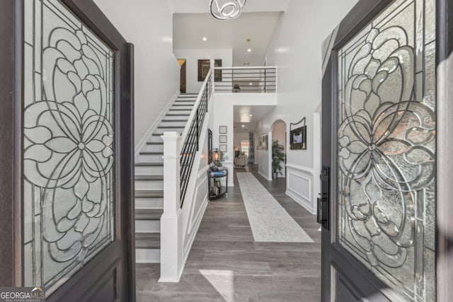 entryway with arched walkways, dark wood-style flooring, stairs, a decorative wall, and recessed lighting