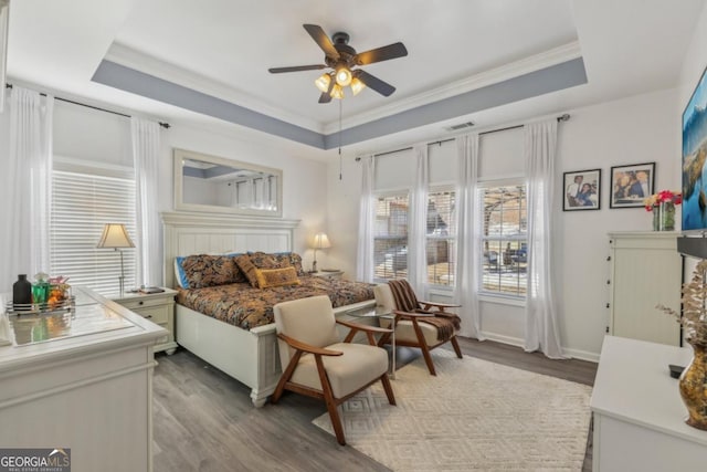 bedroom featuring a raised ceiling, visible vents, light wood-style flooring, ornamental molding, and a ceiling fan