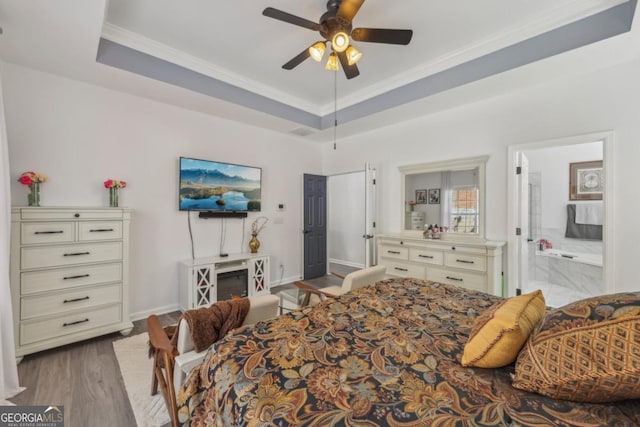 bedroom featuring baseboards, ornamental molding, a raised ceiling, and wood finished floors